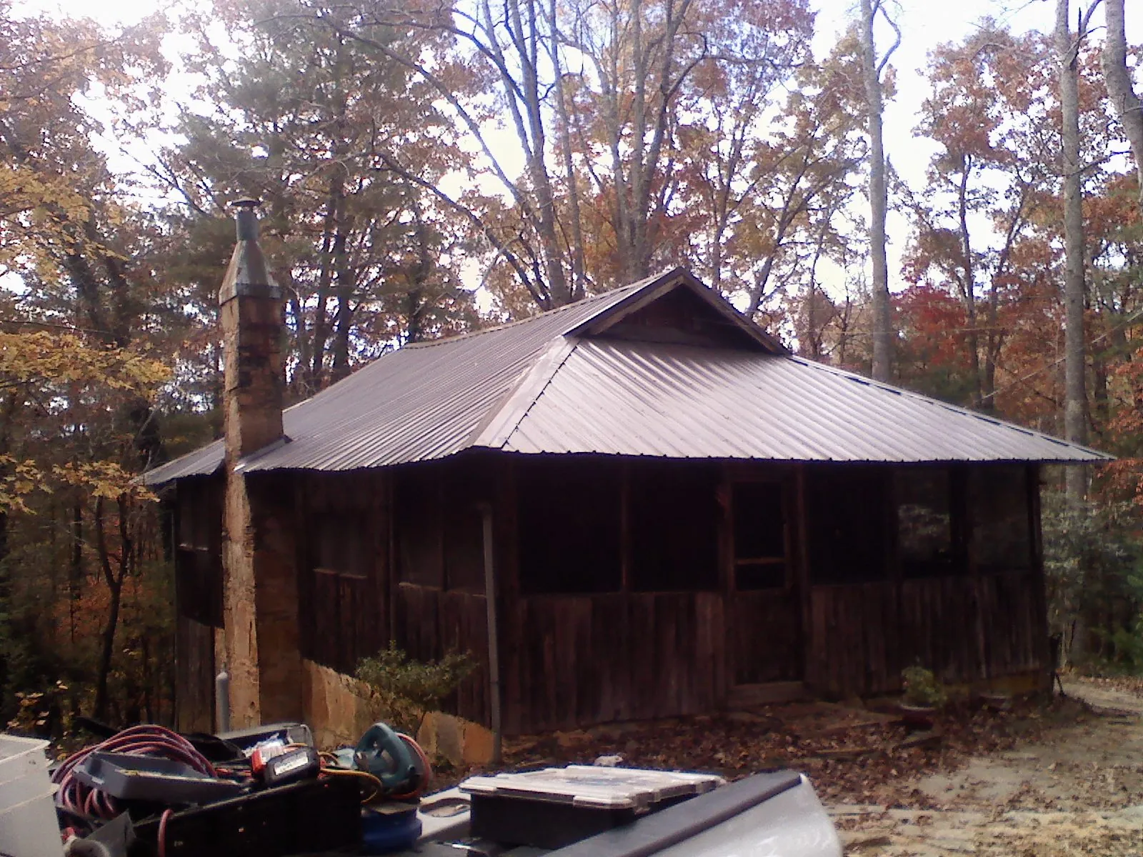 Brown metal hip roof on an old cabin with a stone chimney in Baltimore