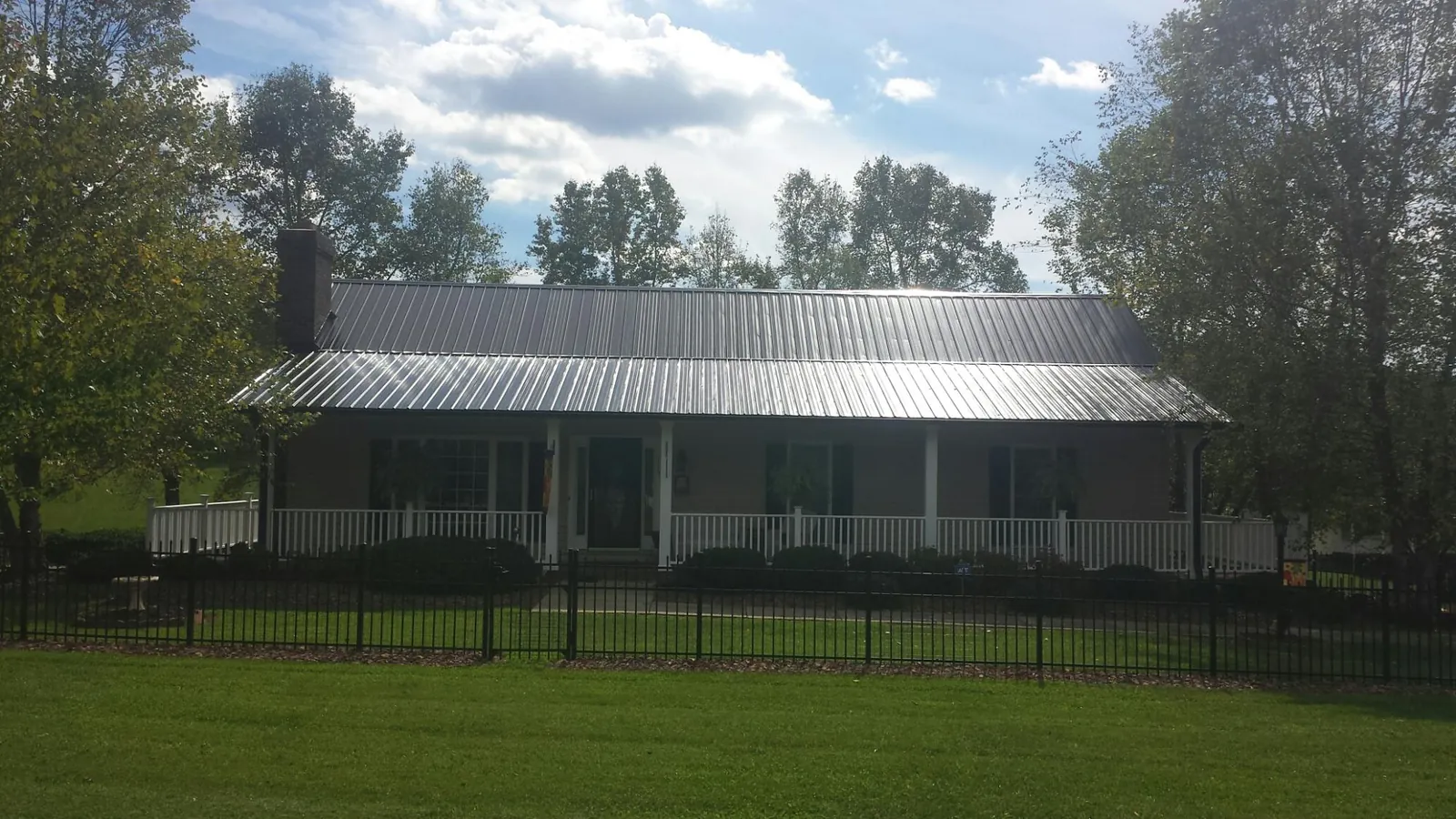 Gray metal roof on a brick ranch with a full width front porch — Gutter Guard Installation work by our crew in Baltimore
