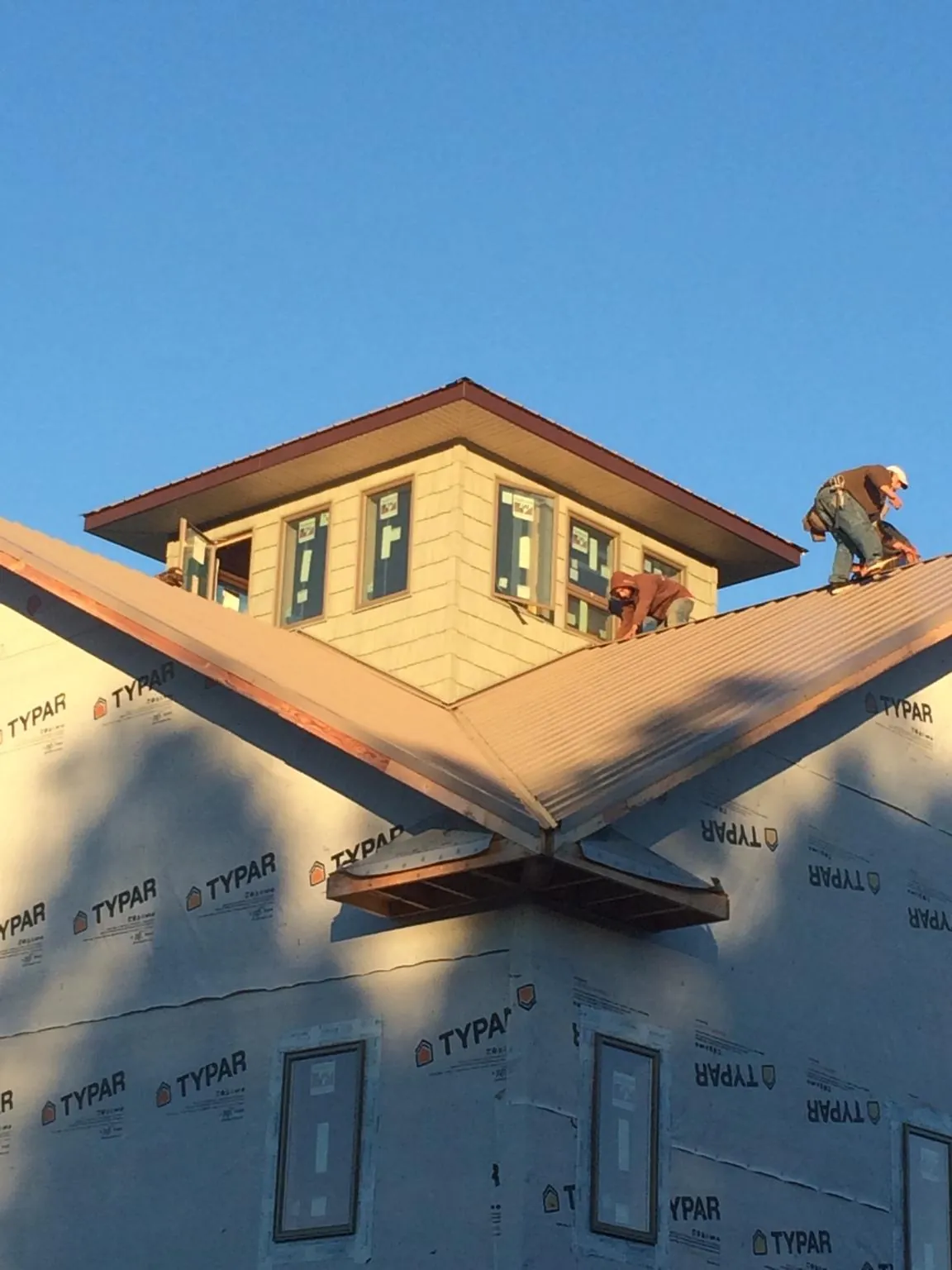 Roofers working around a rooftop cupola on a new metal roof at sunset — Roof Waterproofing in Baltimore by Roofing Brothers